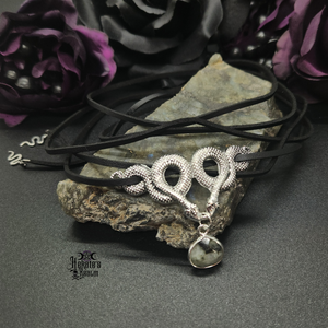 Aliyah Choker displayed in two colors, black leather wrap with silver snakes and white leather wrap with black snakes. Both have a pendant labradorite drop hanging in the middle.